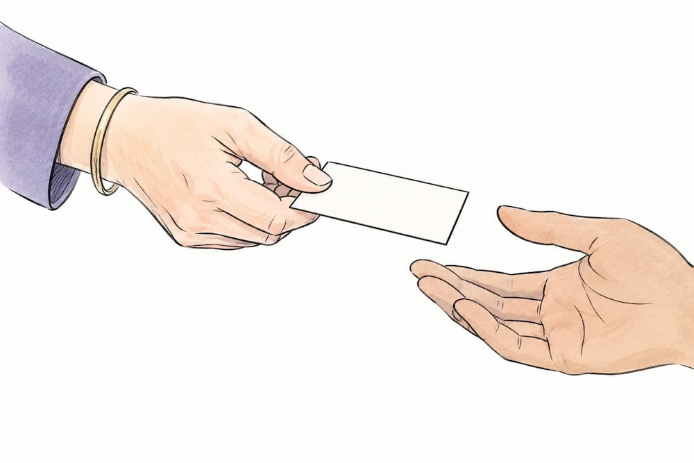 woman's hand offering a business card to another hand.