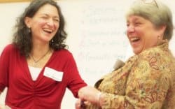 Photo of two women laughing together - Val in networking workshop doing a demo with participant.