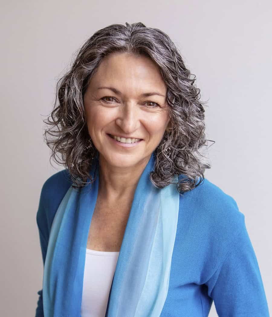 Val Nelson - Coach for Introverts and HSPs - portrait with blue top over white shirt, smiling warmly