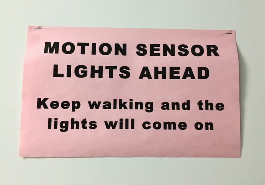 Hallway sign: Motion Sensor Lights Ahead: keep walking and the light will come on.