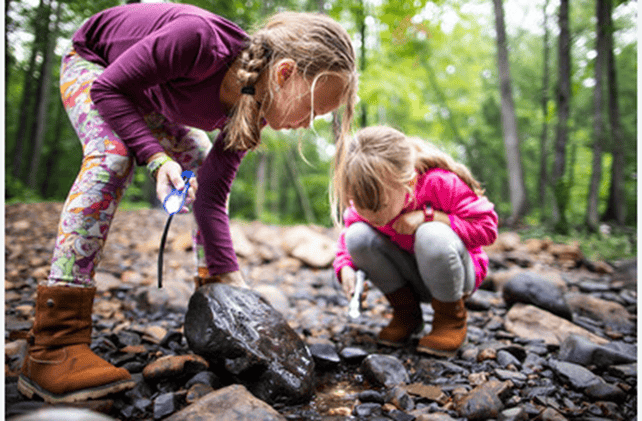 Two young girls looking under rocks just for the heck of it, exploring.