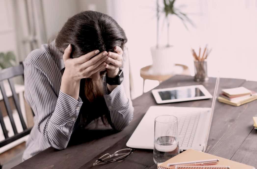photo of woman frustrated at her desk, head in her hands